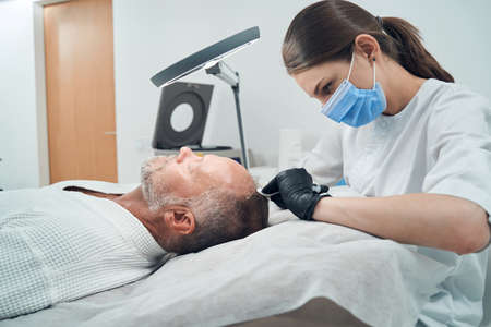 Man getting injection for hair growth at wellness centerの写真素材