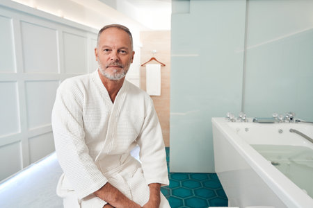 Man sitting on massage table in spa salonの写真素材