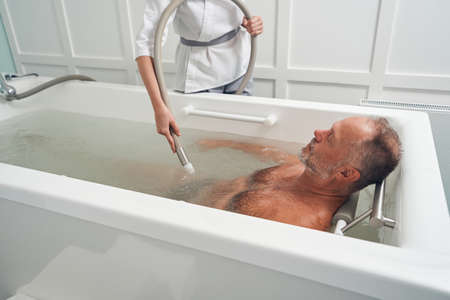 Man having hydrotherapy procedure in spa salonの写真素材