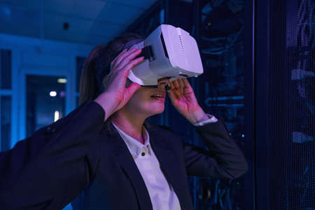 Amazed woman with VR headset in server room