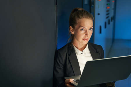 Woman performing maintenance on servers with laptop in data center