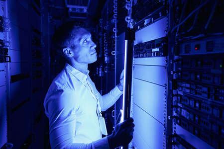 Employee using additional lighting for checking hardware equipment