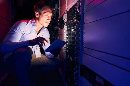 Focused Caucasian system administrator monitoring storage hardwareの写真素材