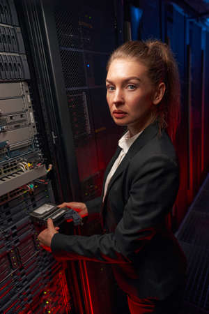 Cute woman administrator checking equipment in data centerの写真素材