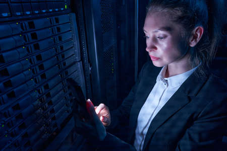 Woman engineer working in datacenter by server storage racksの写真素材