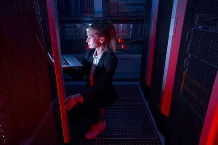 System administrator with laptop examining in server roomの写真素材