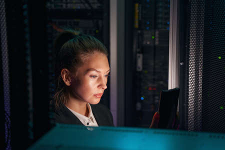 System administrator works near racks with powerful computing equipmentの写真素材