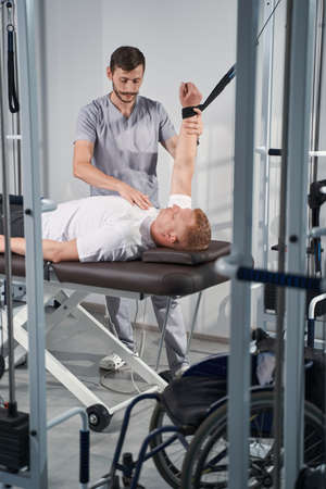 Physiotherapist help man on decompression simulator in rehab roomの写真素材