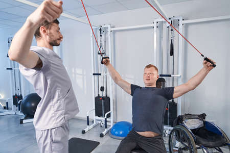 Therapist help patient with cerebral palsy stretch on strength machineの写真素材