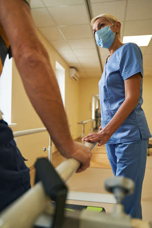 Female physiotherapist assists mature patient in recovery in rehab centerの写真素材