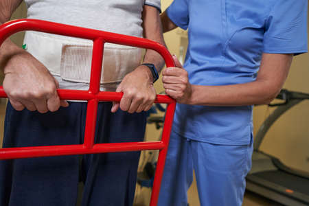Physiotherapist teaching disabled man to use walker at recovery centerの写真素材