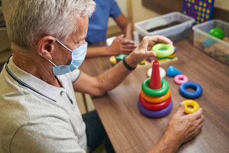 Mature man while recovery of motor skills in rehabilitation center