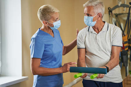 Physical therapist helping stroke victim in rehab center