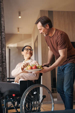 Smiling man bringing fruit for wife with paraleria