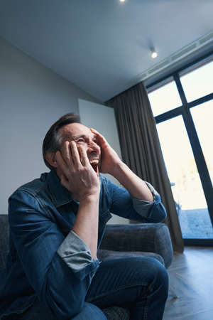 Unhappy male screaming alone at home with pain