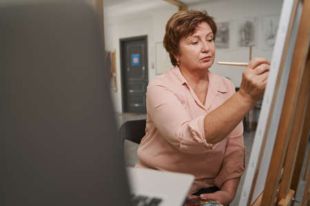 Attentive woman drawing picture in the workshop