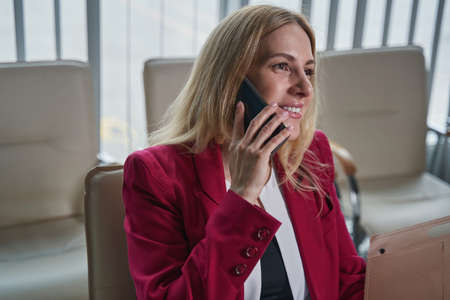 Cheerful woman having a phone call from departure lounge