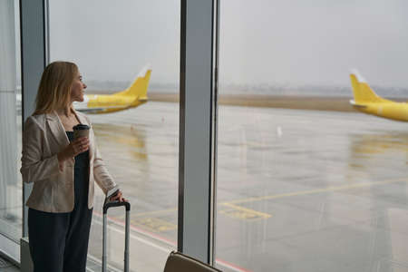 Female watching airplane on takeoff strip from windowの写真素材