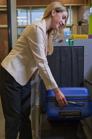 Woman laying her luggage for scanning at security checkの写真素材