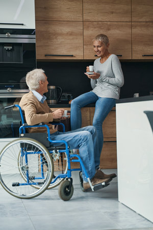 Happy wheelchair user communicating with his wifeの写真素材