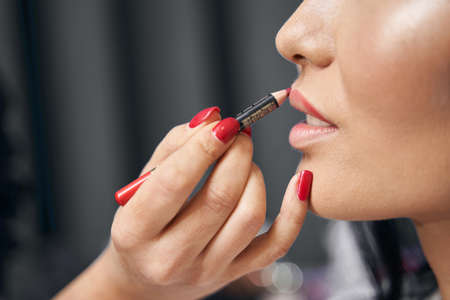 Charming elegant lady with beautiful lips getting visage with lip liner in salon