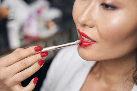 Unrecognized female receiving professional make up in room indoorsの写真素材