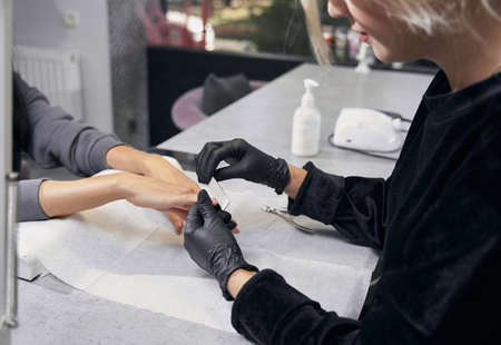 Unrecognized male master doing manicure for client in beauty salonの写真素材