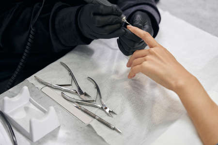 Unrecognized female client receiving manicure hygiene in beauty centerの写真素材