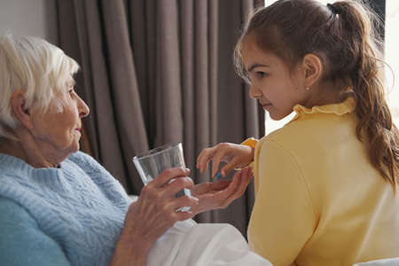 Responsible kid reminding grandmother to take medicationの写真素材