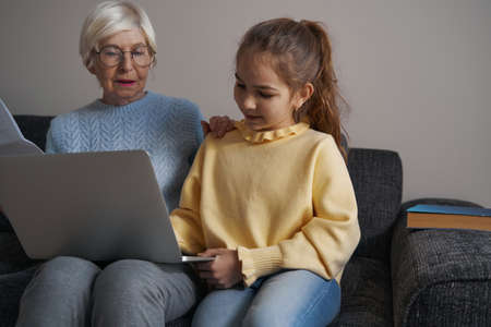 Intent child and grandma watching laptop screen at homeの写真素材