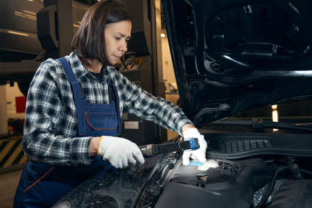 Skillful female mechanic doing car diagnostics at service station