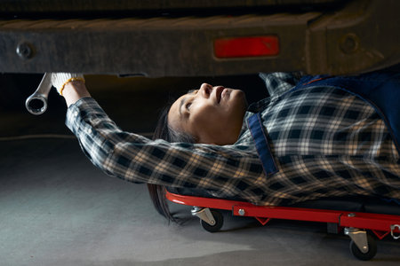 Busy repairwoman working at service station and examining carの写真素材