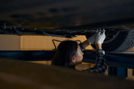 Skillful brunette woman using mechanic tools to fix a carの写真素材