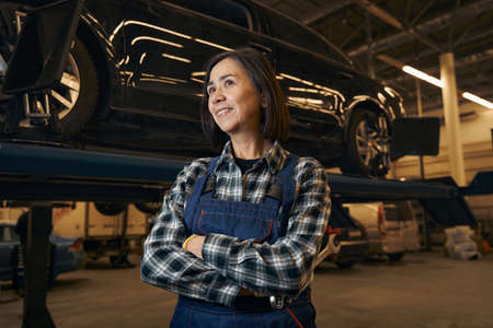 Proud female mechanic happily posing at her workplaceの写真素材