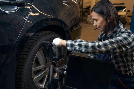 Strong joyful woman replacing car tyre with ease and confidence