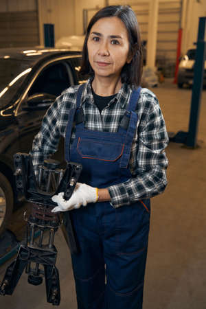 Strong and skilled woman changing car tyre at a workshopの写真素材
