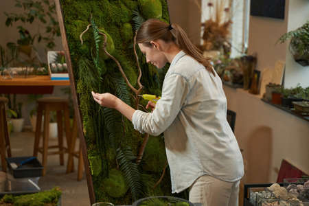Smiling woman making picture with green plants