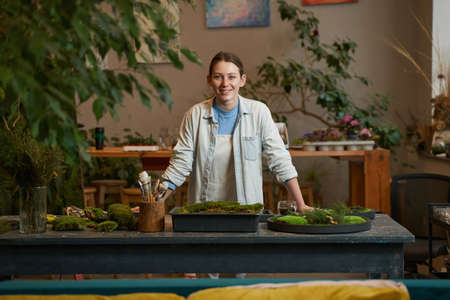 Pretty woman making pictures with green plants