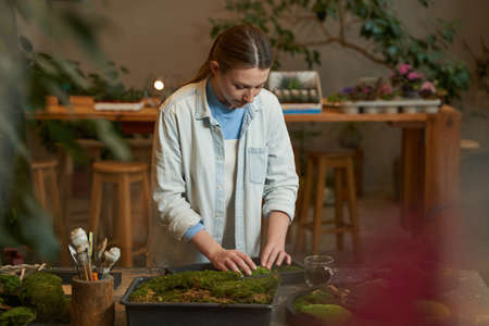 Pretty woman making picture with green plants