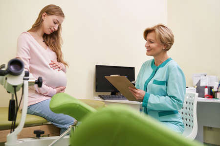Happy mature medical worker consulting her pregnant clientの写真素材