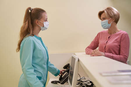 Pleased blonde female person talking to receptionist