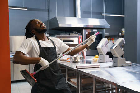 Funny chef cleaning floor at the kitchen
