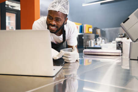 Man standing near the table and looking on computerの写真素材