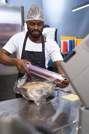 Male in black apron preparing ingredients in the kitchenの写真素材