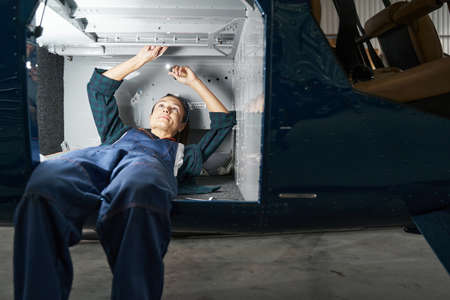 Focused woman mechanic inspecting and modernization details of jet aircraftの写真素材