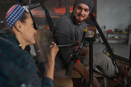 Bearded man mechanic looking to the female in hangarの写真素材