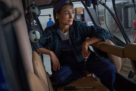 Woman engineer with metal tool in hand sitting in private jet airplaneの写真素材