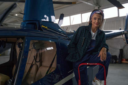 Brunette female mechanic in overall looking away isolated on copter background