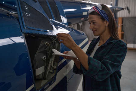 Charming joyful female examining details of helicopter in hangar