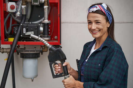 Beautiful woman in shirt holing refueling hose isolated on white backgroundの写真素材